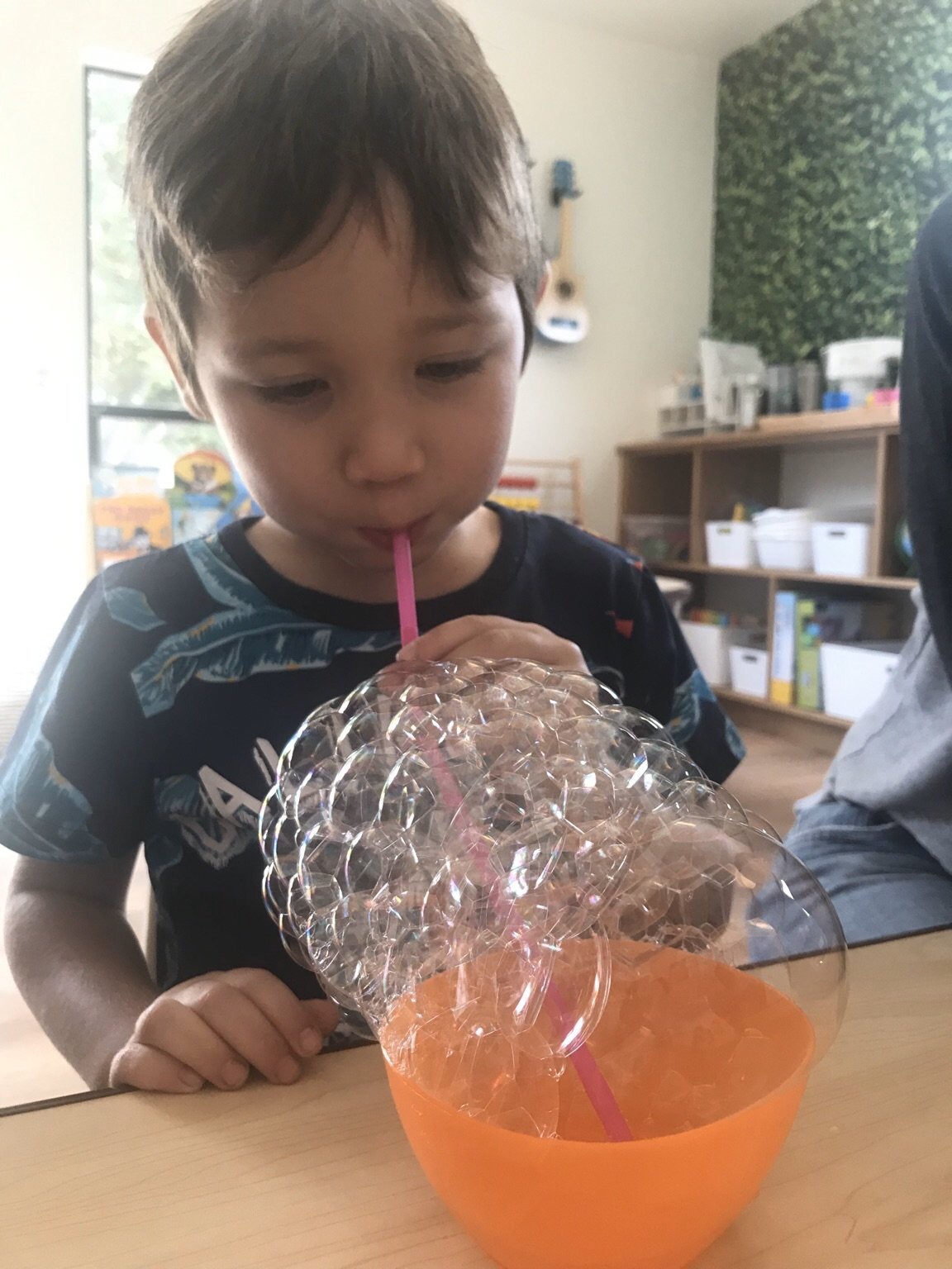 Science - student blowing bubbles in cup for science experiment